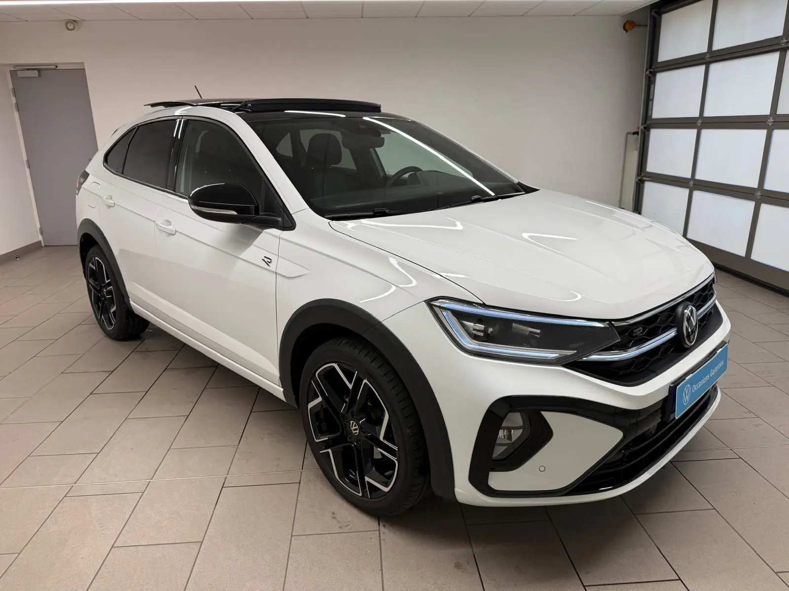 Volkswagen Taigo blanc pur toit noir en 3/4 avant droit avec jantes R-Line et toit ouvrant électrique visible.