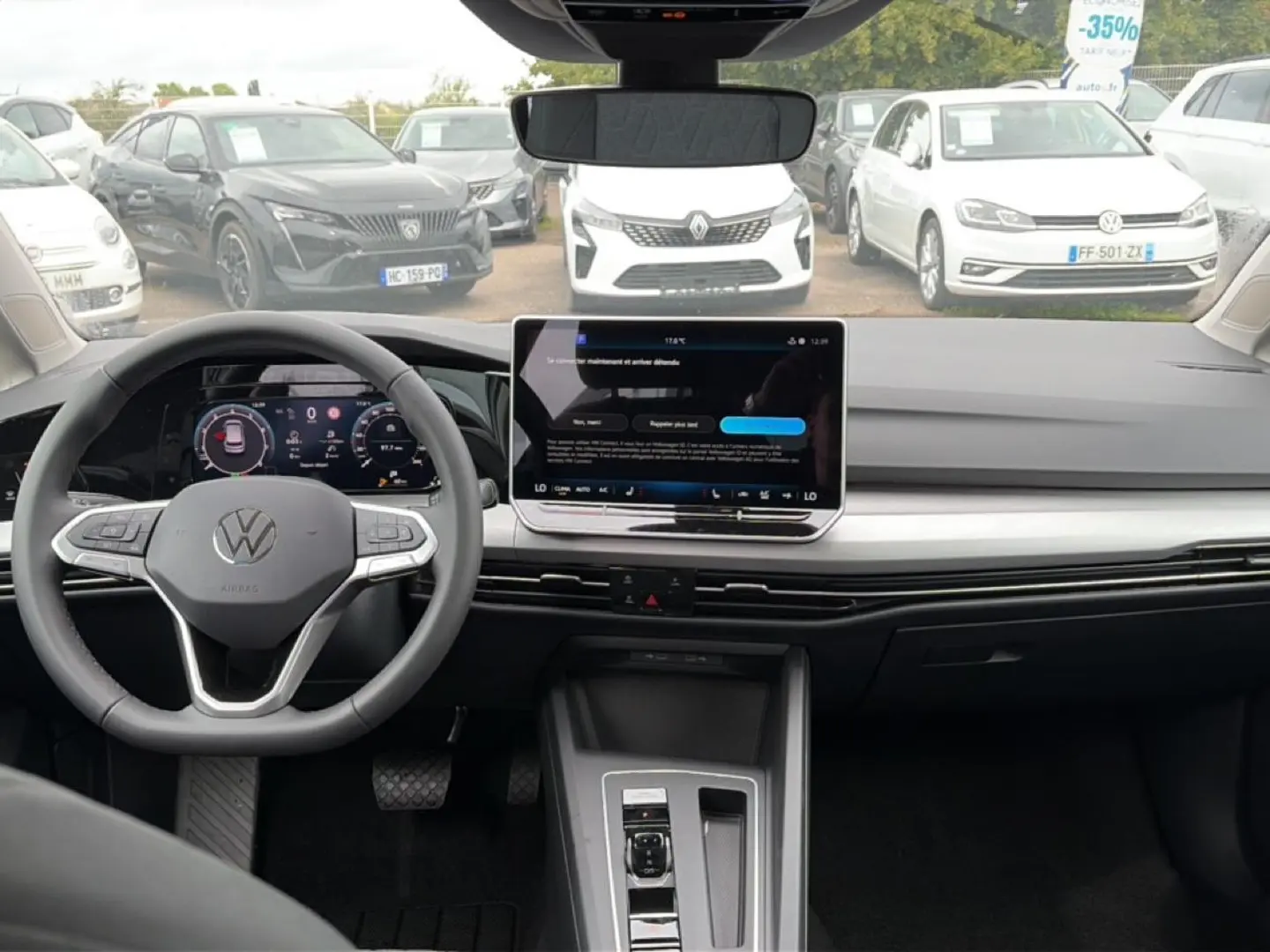 Vue intérieure avant de la Volkswagen Golf 1.5 bleu glacier, avec tableau de bord numérique et écran tactile central.