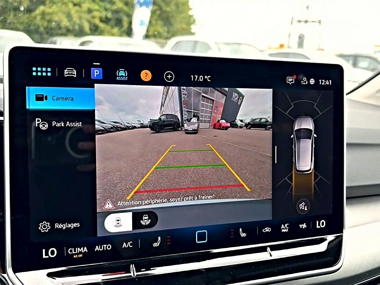 Écran tactile intérieur montrant la caméra de recul et l’assistance au stationnement d’une Volkswagen Golf bleu glacier.