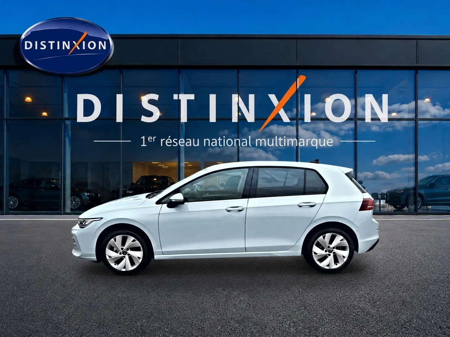Profil côté gauche d'une Volkswagen Golf 1.5 etsi evo2 116 life dsg7 bleu glacier, garée devant une vitrine Distinxion.
