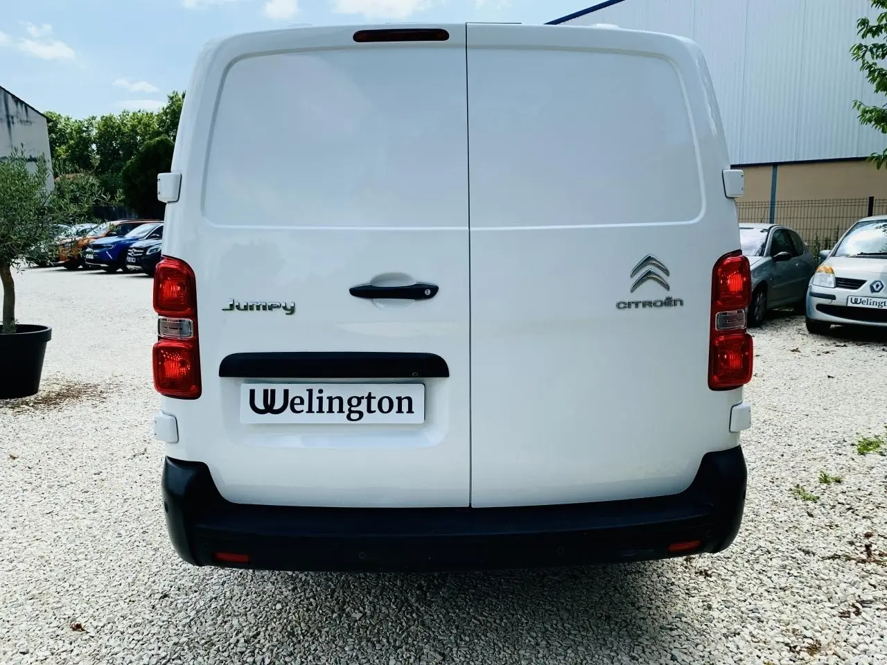 Vue arrière d'un utilitaire Citroën Jumpy blanc avec portes battantes et feux rouges visibles.