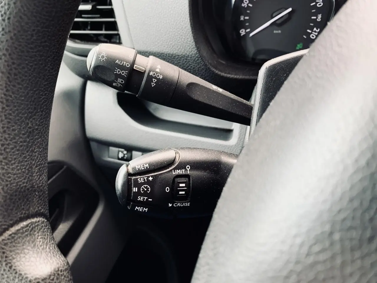 Gros plan sur les commandes au volant du Citroën Jumpy blanc 2020, mettant en valeur le régulateur de vitesse et les feux automatiques.