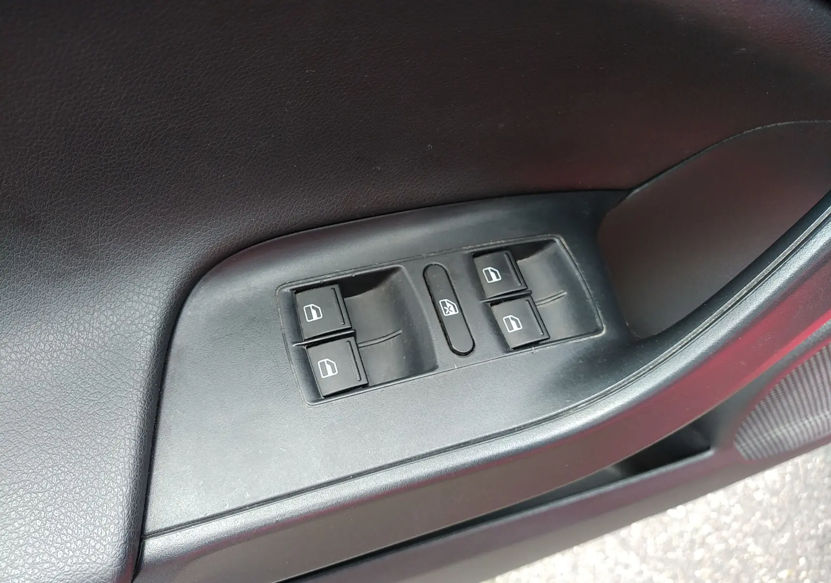 Gros plan sur les commandes des vitres électriques côté conducteur d'une SEAT Ibiza ST rouge de 2015.