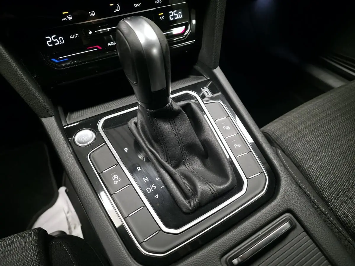 Le levier de vitesse automatique noir de la Volkswagen Passat SW 2021 vu de dessus avec console et sièges en tissu gris.