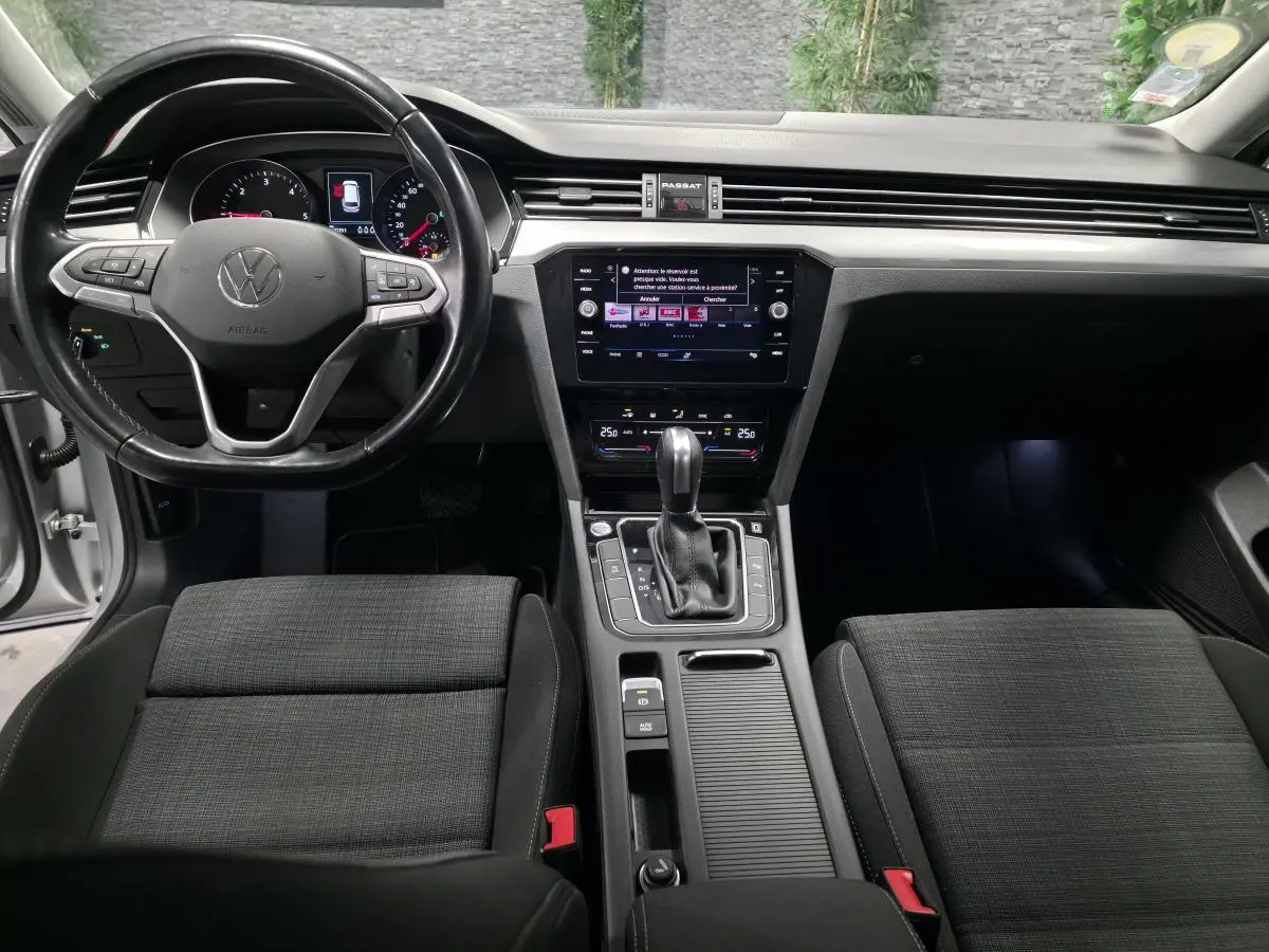 Intérieur avant de la Volkswagen Passat SW 2021, vue centrale sur tableau de bord et console, sièges tissu gris foncé.