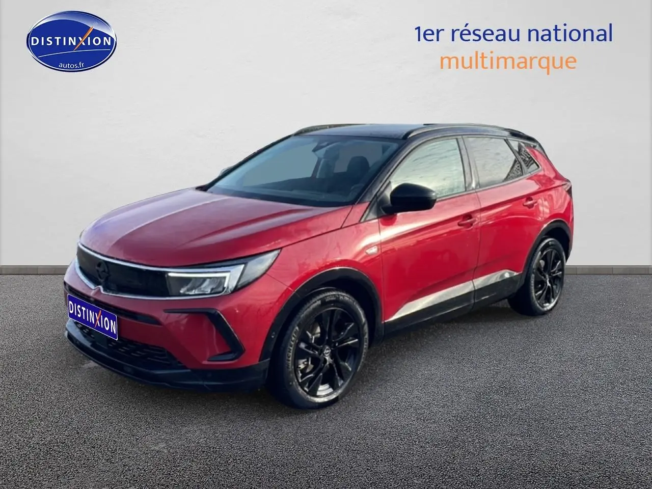 Opel Grandland rouge 3/4 avant droit avec toit noir et jantes alliage noires sur fond neutre.