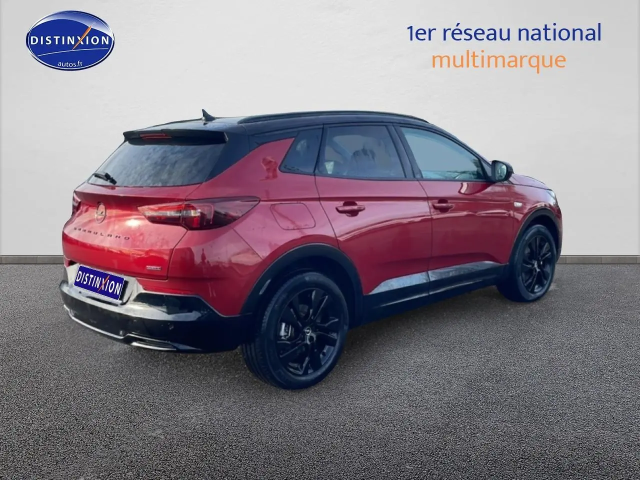 Vue 3/4 arrière droite d’un Opel Grandland rouge 2024 avec toit noir et jantes noires.