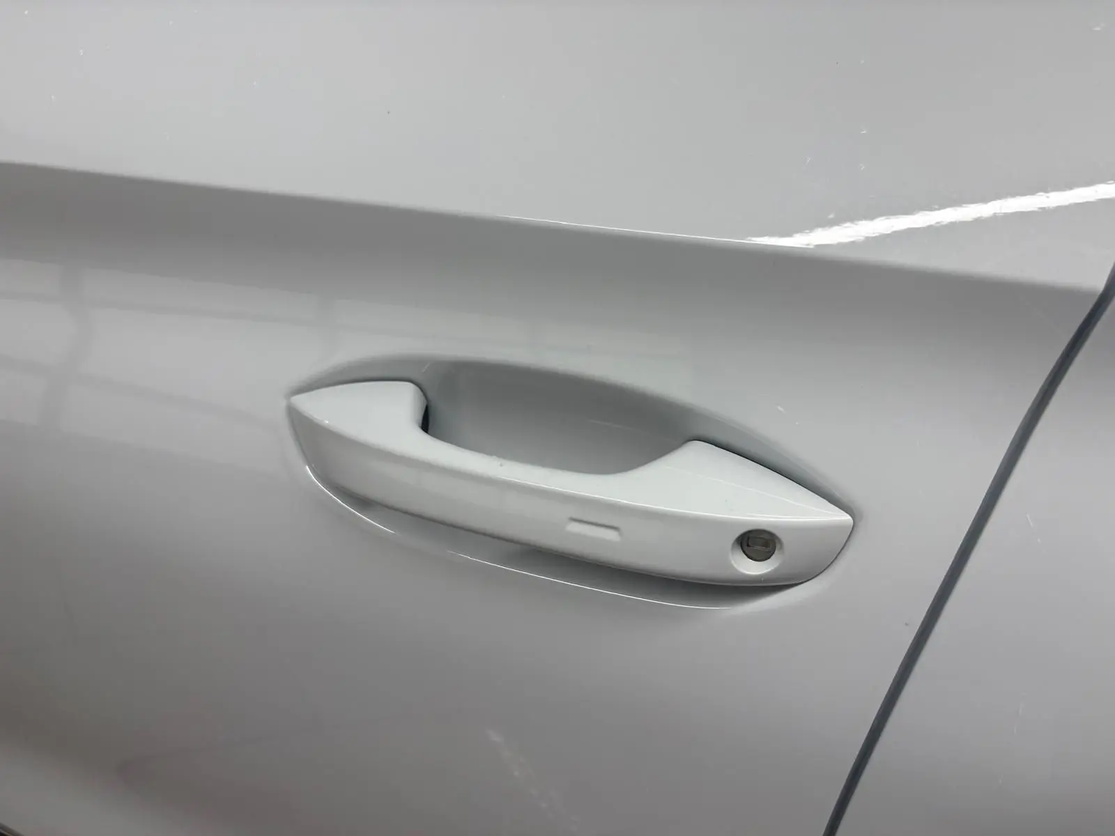 Poignée de porte côté droit de la CUPRA Leon 2024 en blanc Nevada, avec serrure intégrée visible.