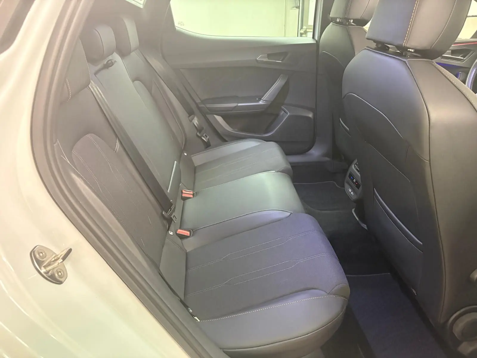 Vue intérieure côté gauche des sièges arrière en cuir noir du CUPRA Leon blanc Nevada 2024 avec toit ouvrant panoramique.