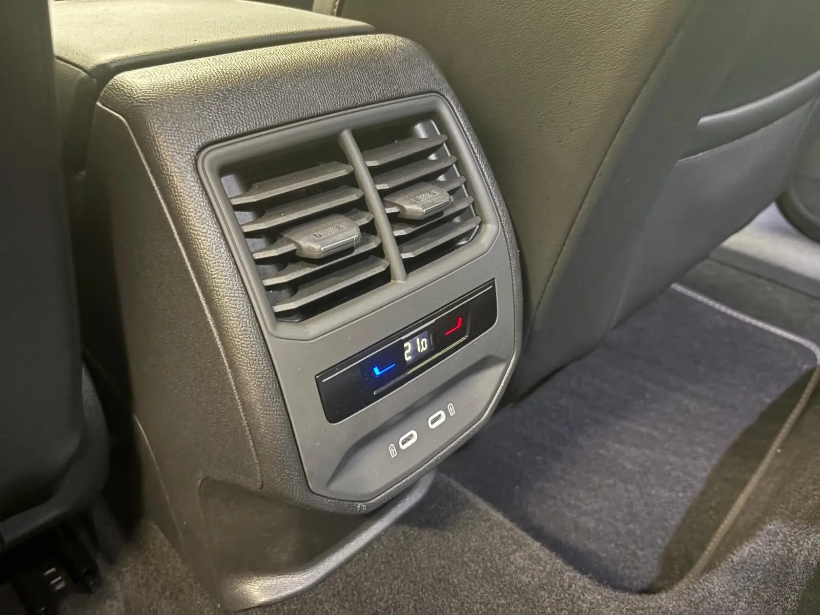 Détail de la console arrière avec commandes de climatisation et ports USB dans l'habitacle noir du CUPRA Leon 2024.
