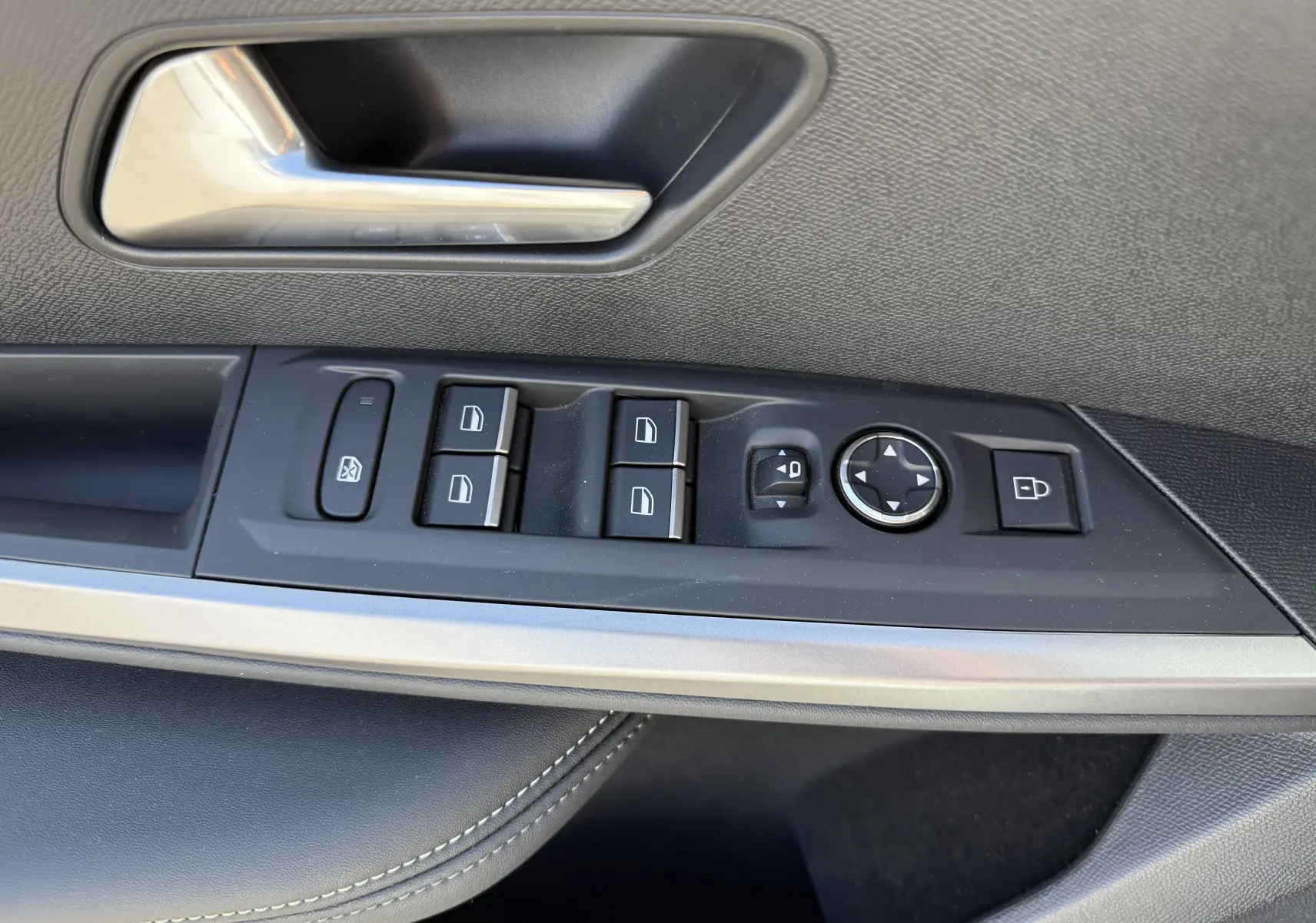 Gros plan sur la commande des vitres et rétroviseurs côté conducteur du Peugeot 5008 Hybrid blanc, intérieur noir.