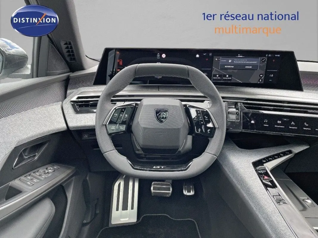 Vue intérieure centrée sur le volant GT du Peugeot 5008 Hybrid blanc Okenite avec tableau de bord numérique et finitions modernes.