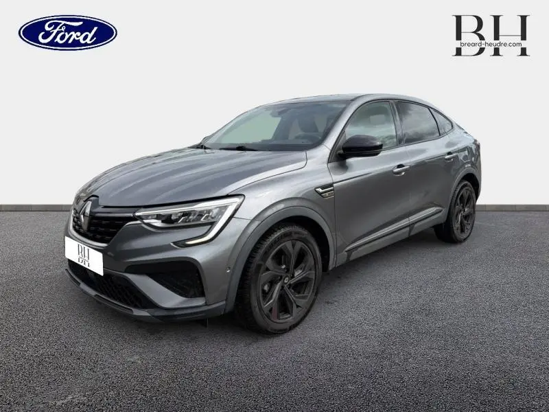 Renault Arkana gris métallisé en vue 3/4 avant droit, avec jantes noires et signature lumineuse LED distinctive.