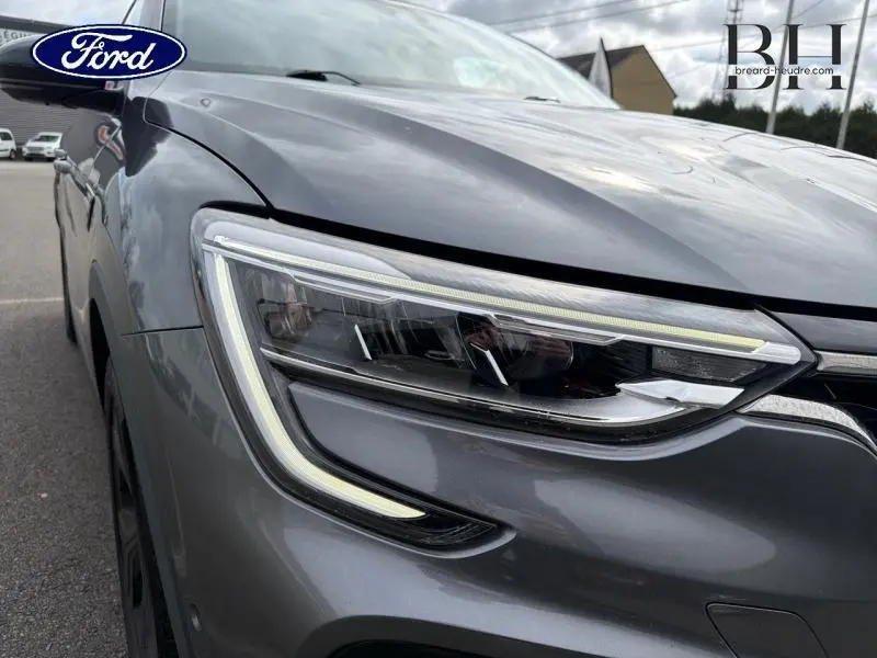 Gros plan sur le phare avant gauche d'un Renault Arkana gris métallisé, soulignant son design LED moderne.