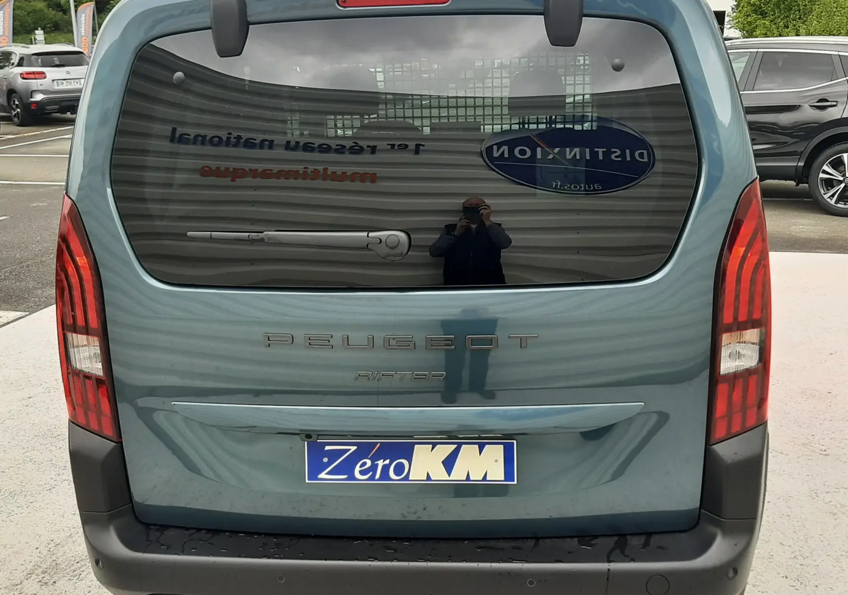 Vue arrière du Peugeot Rifter bleu Kiama 2026 avec hayon fermé et feux arrière verticaux allumés.