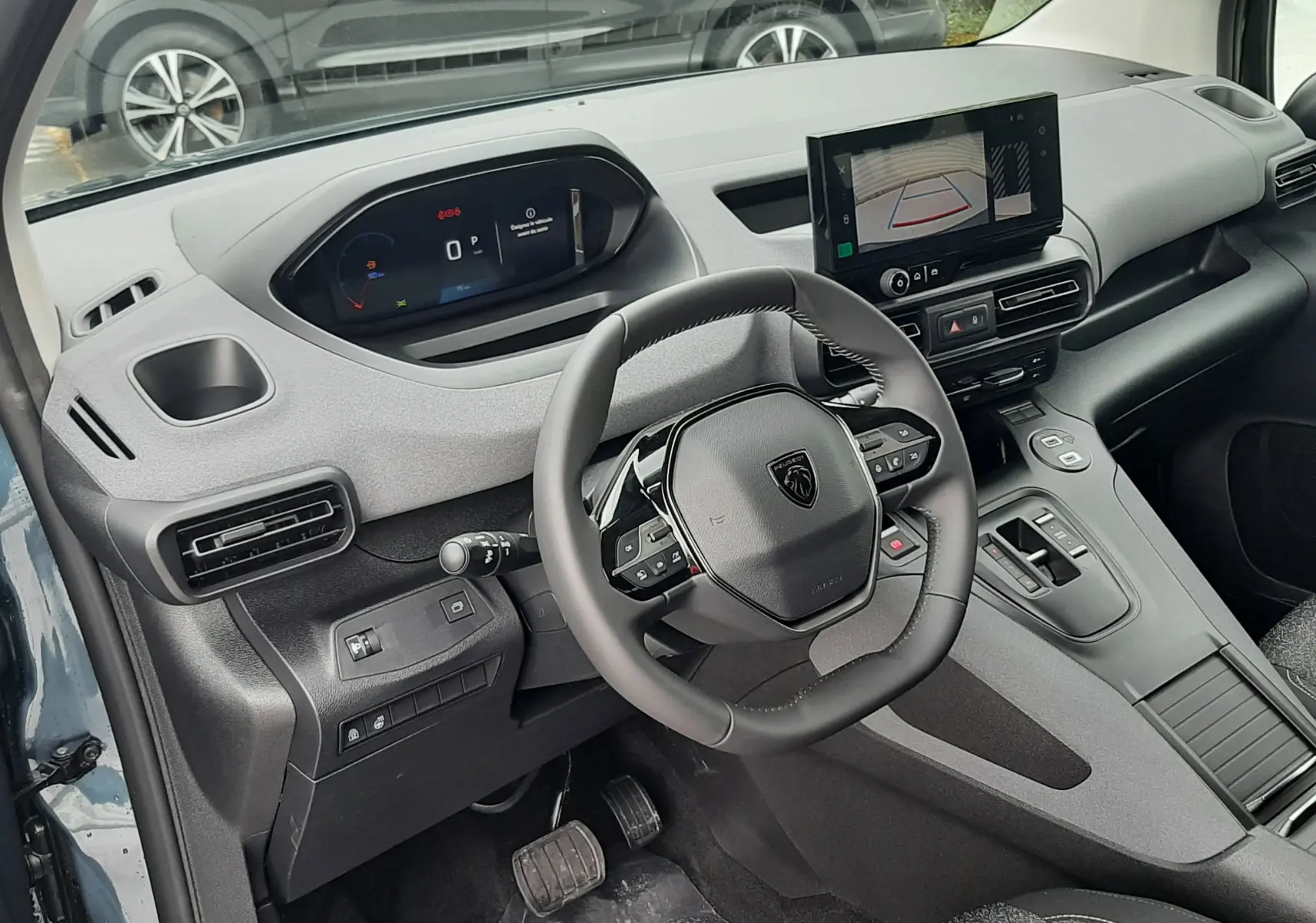 Vue intérieure côté conducteur du Peugeot Rifter 2026 bleu Kiama, tableau de bord moderne avec écran tactile et volant multifonction.