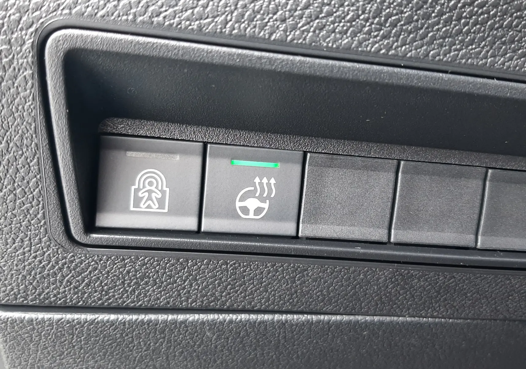 Gros plan sur les boutons de commande du tableau de bord du Peugeot Rifter 2026, plastique noir texturé.