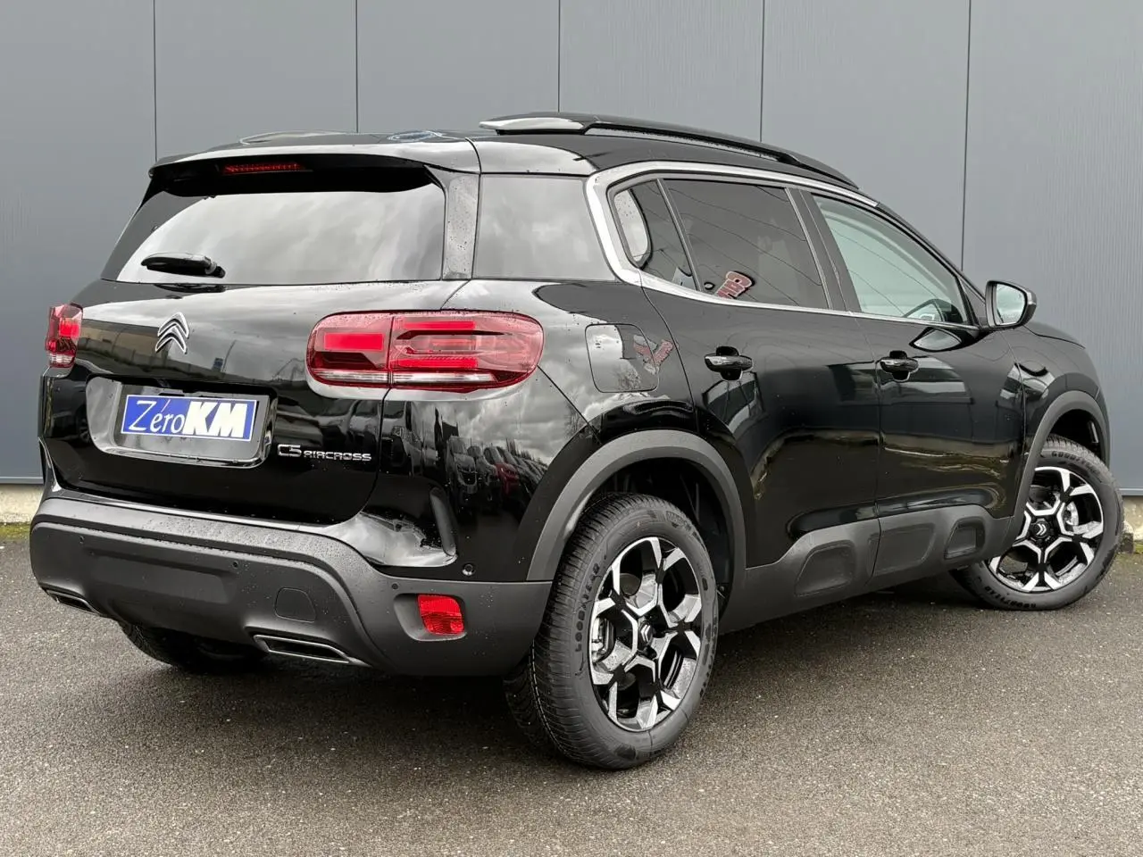 Vue 3/4 arrière droite du Citroën C5 Aircross noir Perla avec jantes alliage bi-ton et barres de toit noires.
