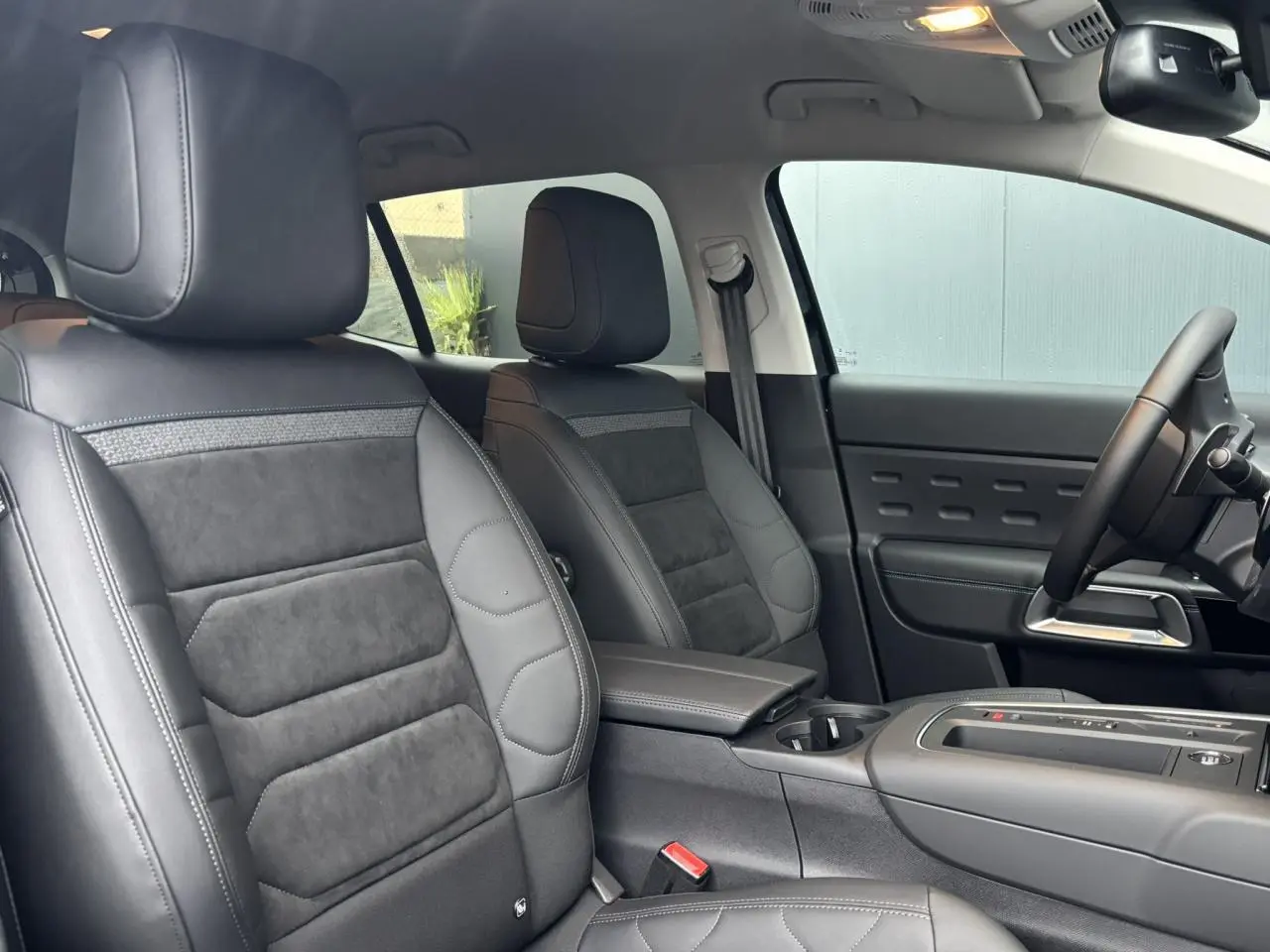Vue intérieure côté droit montrant les sièges avant en Alcantara noir avec surpiqûres bleues et console centrale du Citroën C5 Aircross.