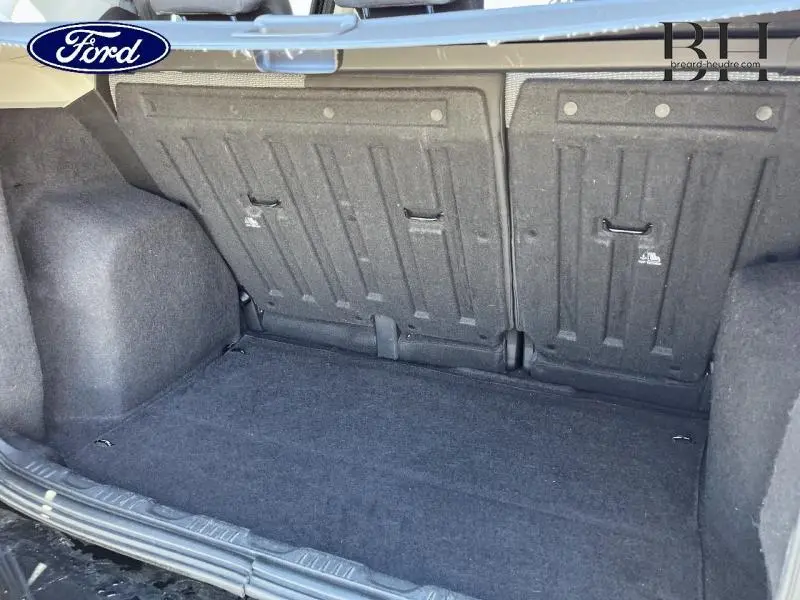 Coffre ouvert du Ford EcoSport noir Scala 2016, vue intérieure montrant la banquette arrière rabattable et le tapis de coffre.