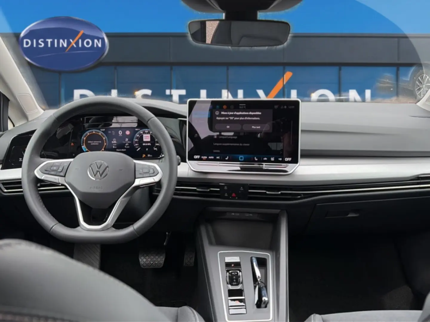 Vue intérieure avant centrée sur le tableau de bord et volant gris d’une Volkswagen Golf 2026 avec écran tactile et digital cockpit.