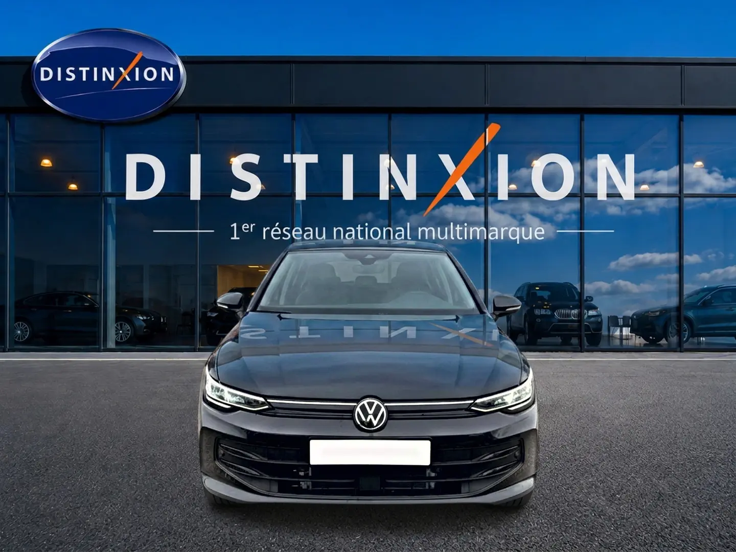 Volkswagen Golf 2026 noire vue de face, avec calandre épurée et phares LED allumés devant showroom Distinxion.