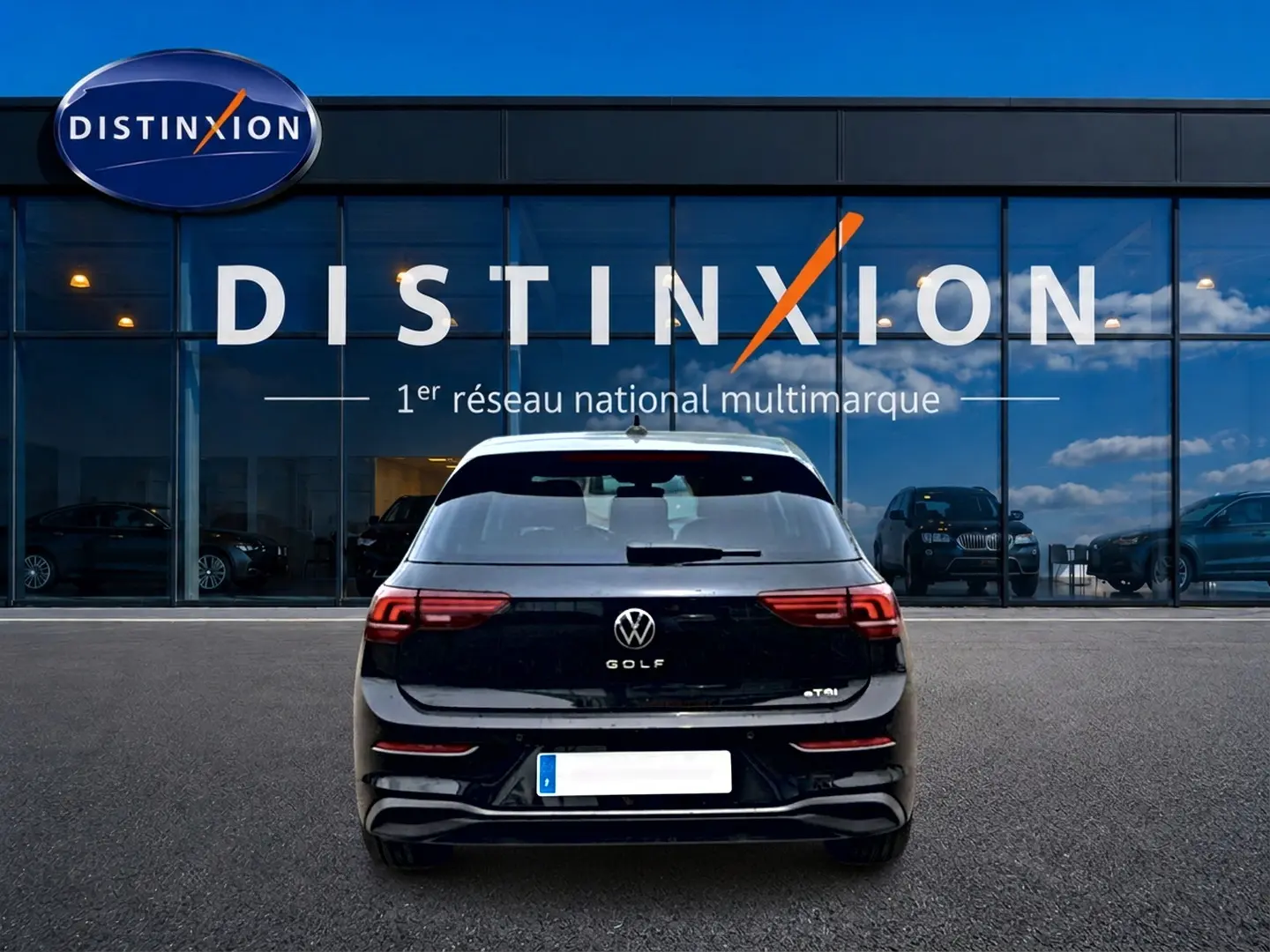 Vue arrière d'une Volkswagen Golf noire 2026 garée devant une vitrine avec enseigne Distinxion.