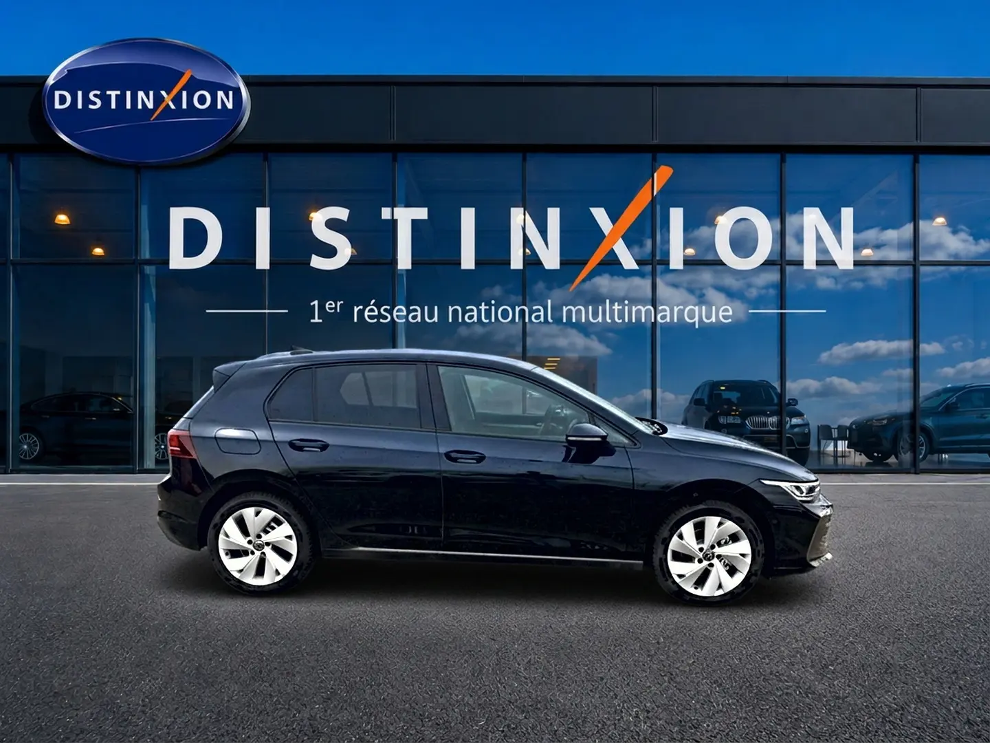 Profil côté gauche d'une Volkswagen Golf noire 2026 garée devant une vitrine avec logo Distinxion.