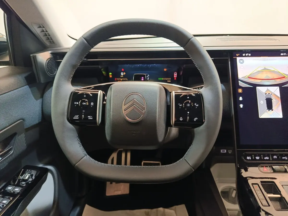 Vue rapprochée du volant cuir noir du Citroën C5 hybride 2026 avec tableau de bord digital et écran tactile de navigation.