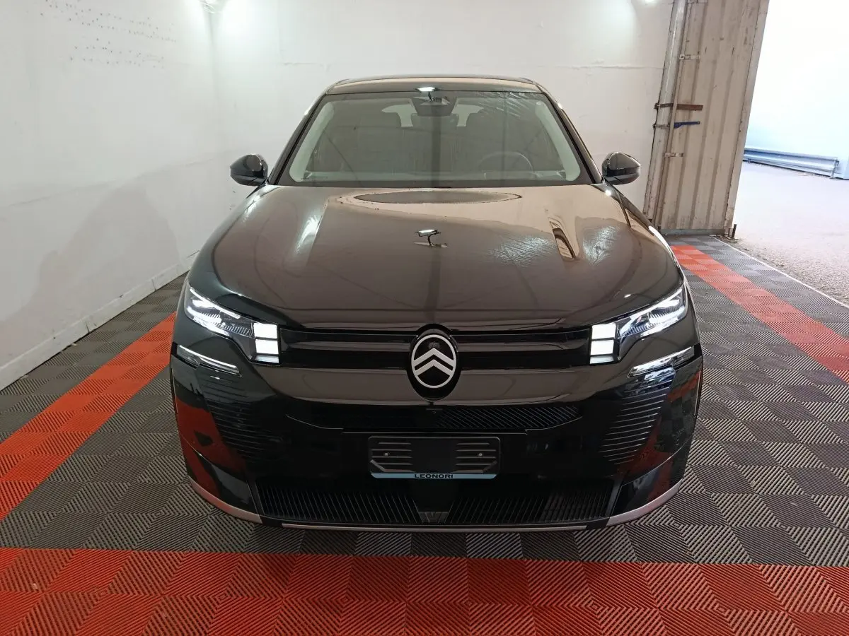 Vue frontale d'une Citroën C5 Hybride noire avec phares LED allumés dans un garage.