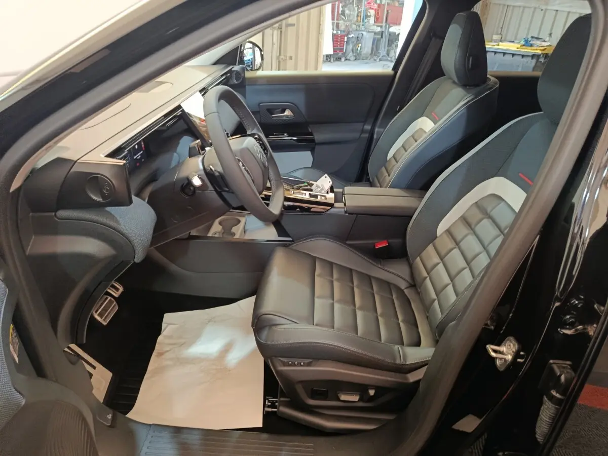 Vue intérieure côté conducteur de la Citroën C5 Hybride noire 2026, sièges cuir noir et tableau de bord moderne.
