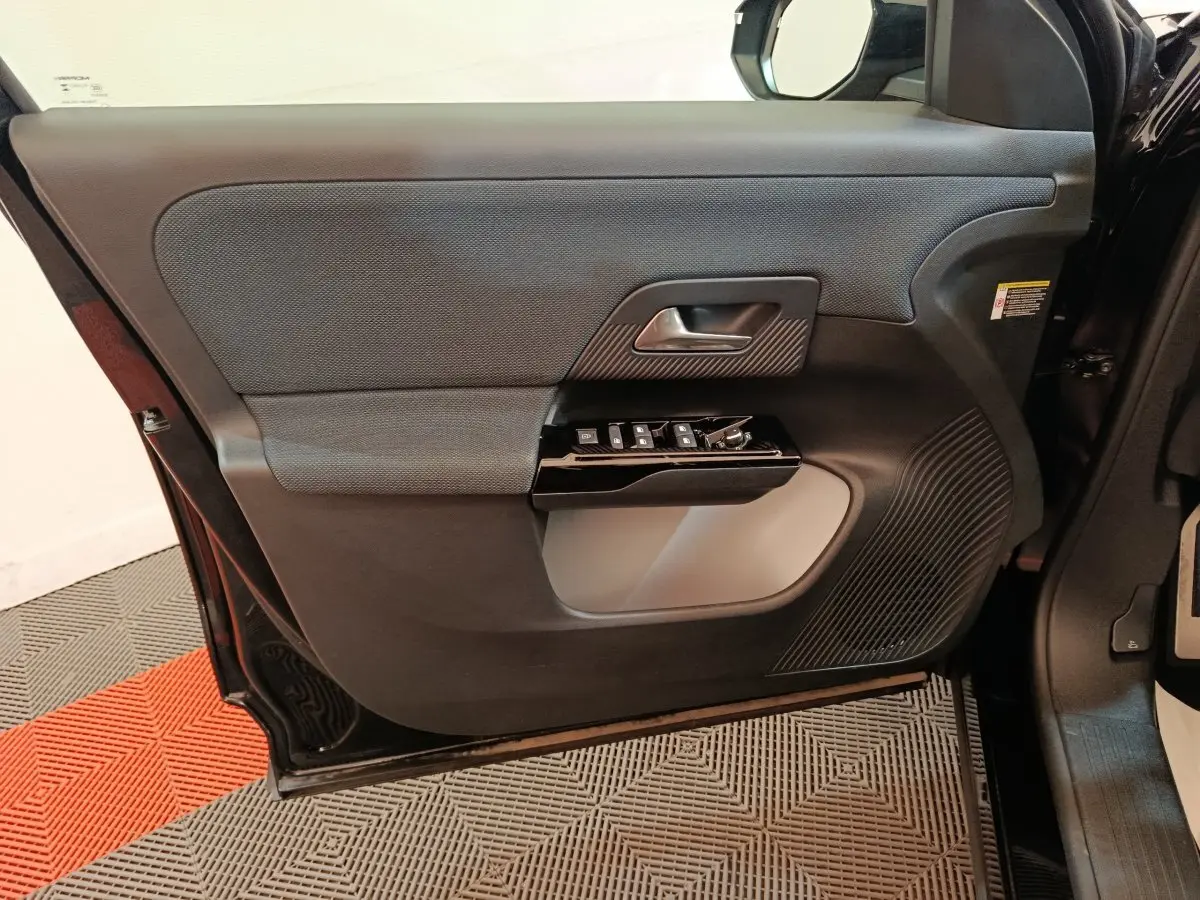 Vue intérieure de la porte avant gauche noire du Citroën C5 Hybride 2026 avec commandes de vitres et poignée intégrée.