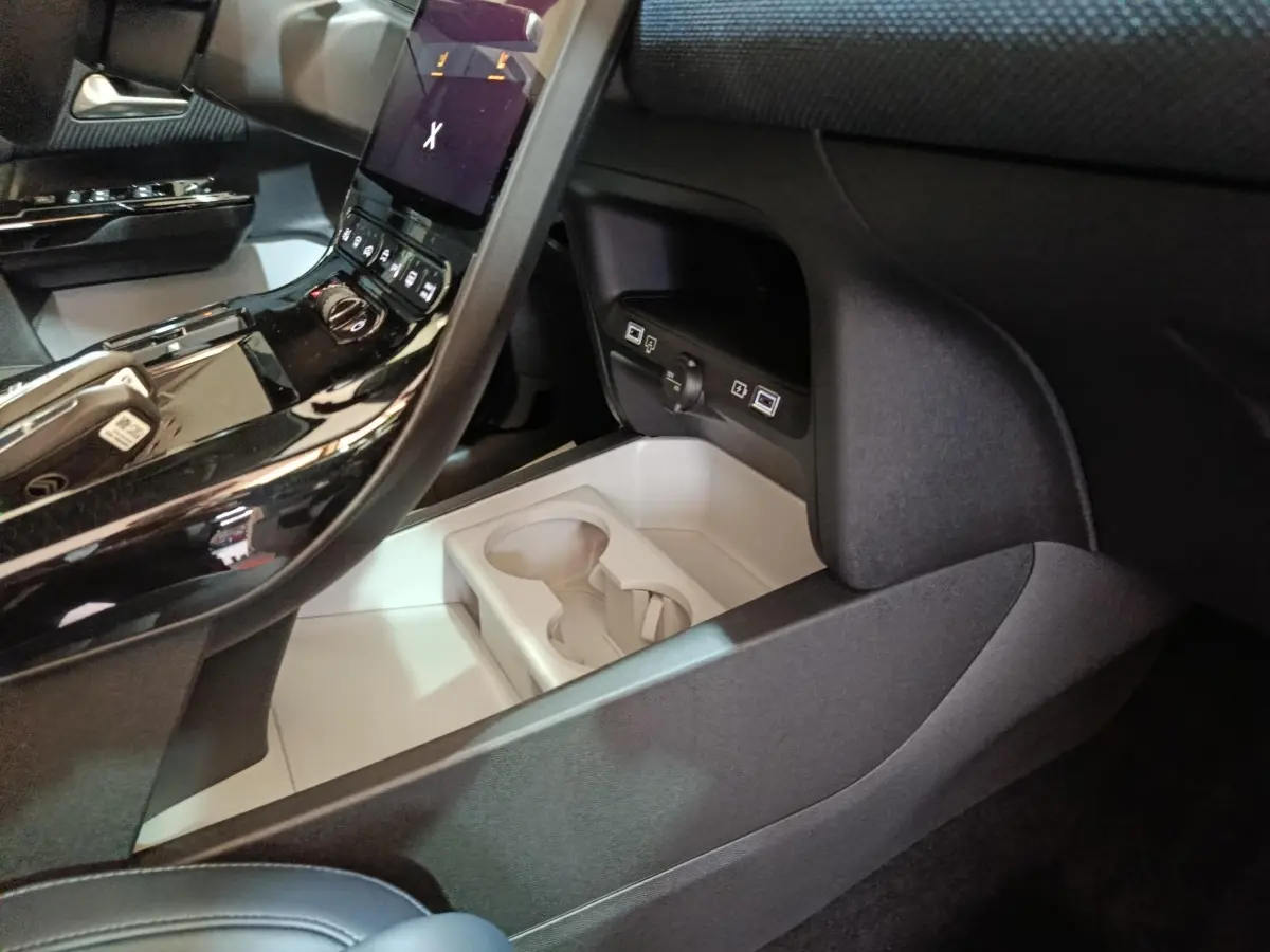 Intérieur de la Citroën C5 Hybride 2026, vue console centrale noire brillante avec porte-gobelets et prises USB.