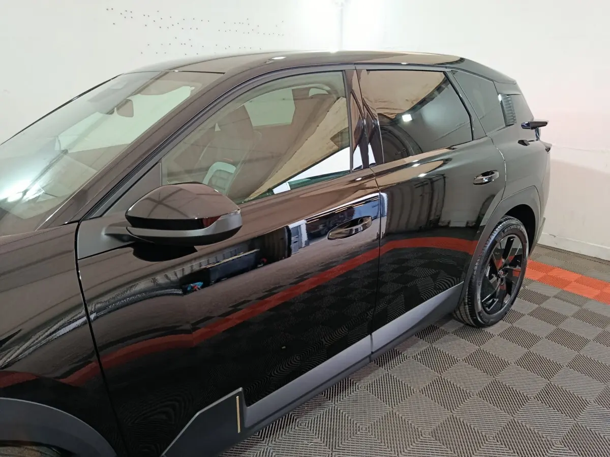 Vue latérale côté gauche d'une Citroën C5 Hybride noire avec jantes noires et détails de carrosserie modernes.