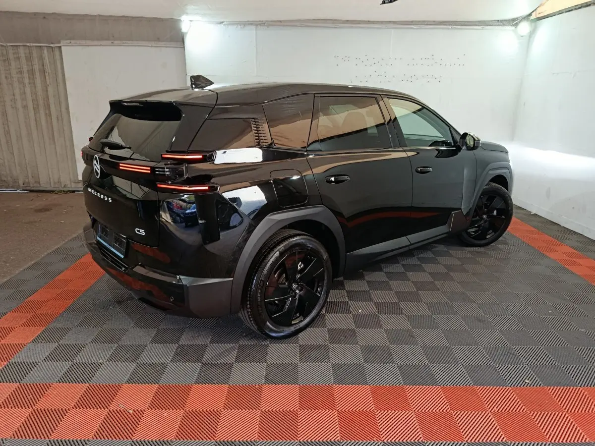 Vue 3/4 arrière droit d'une Citroën C5 noire avec feux arrière LED et jantes noires dans un garage.