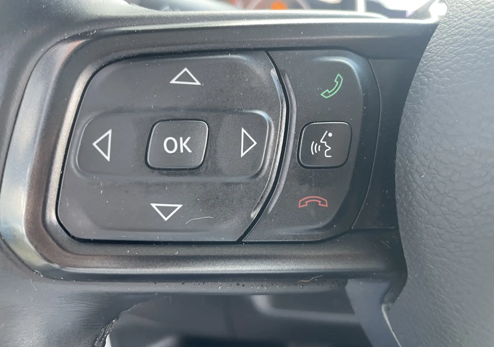 Gros plan sur les commandes multifonctions noires du volant du Jeep Wrangler blanc 2018, boutons directionnels et appels.