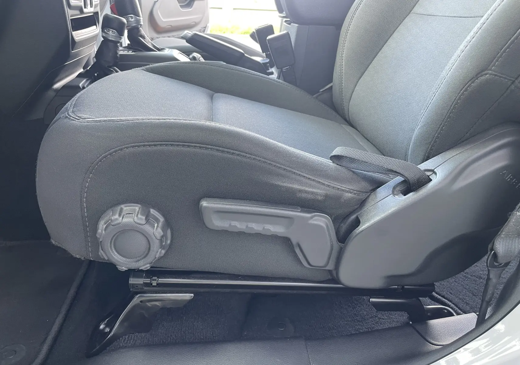 Gros plan sur le siège avant droit en tissu gris noir du Jeep Wrangler blanc 2018, montrant les réglages manuels.