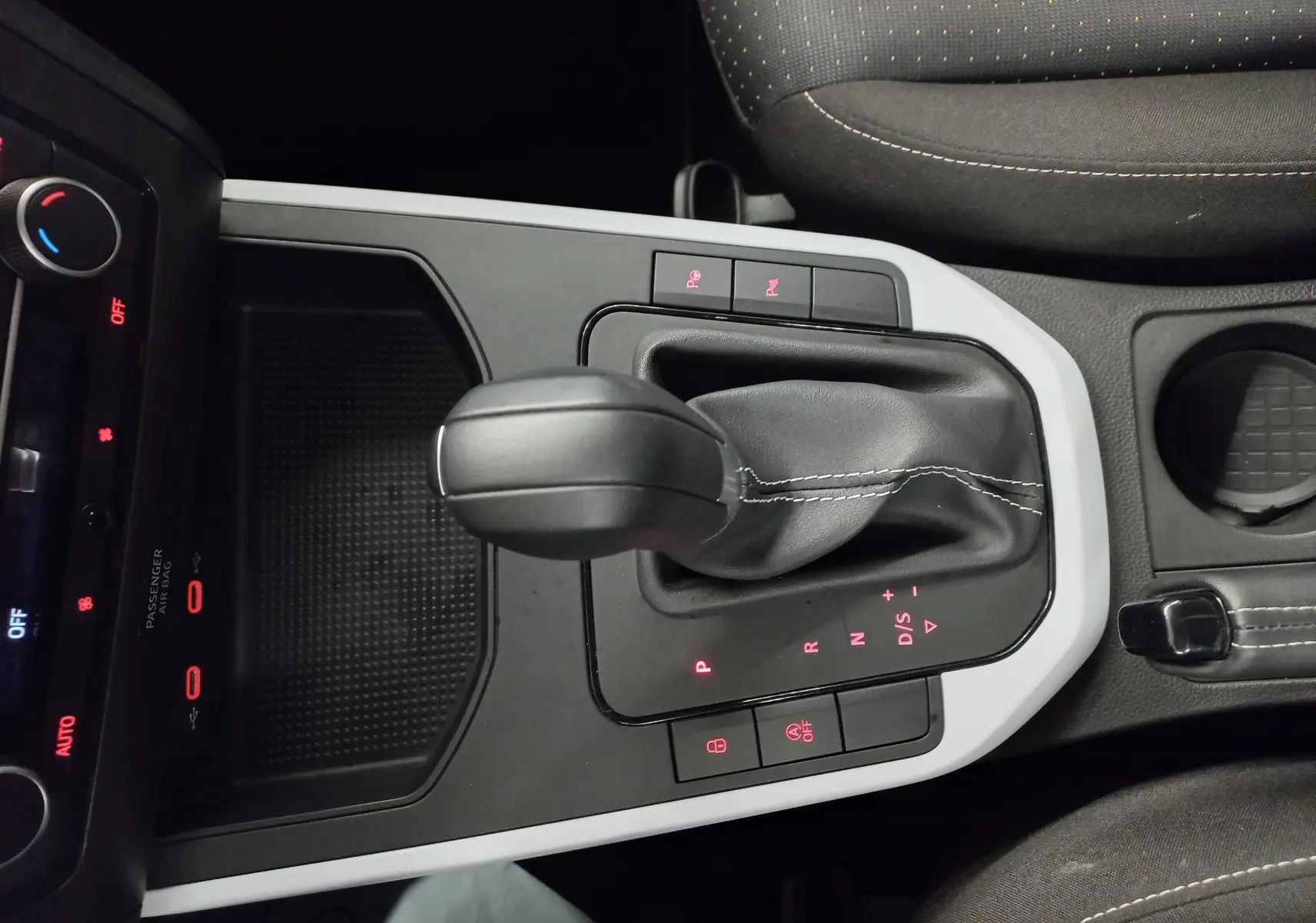 Gros plan sur la console centrale de la SEAT Arona 2025 avec levier de boîte automatique et éclairage rouge des commandes.