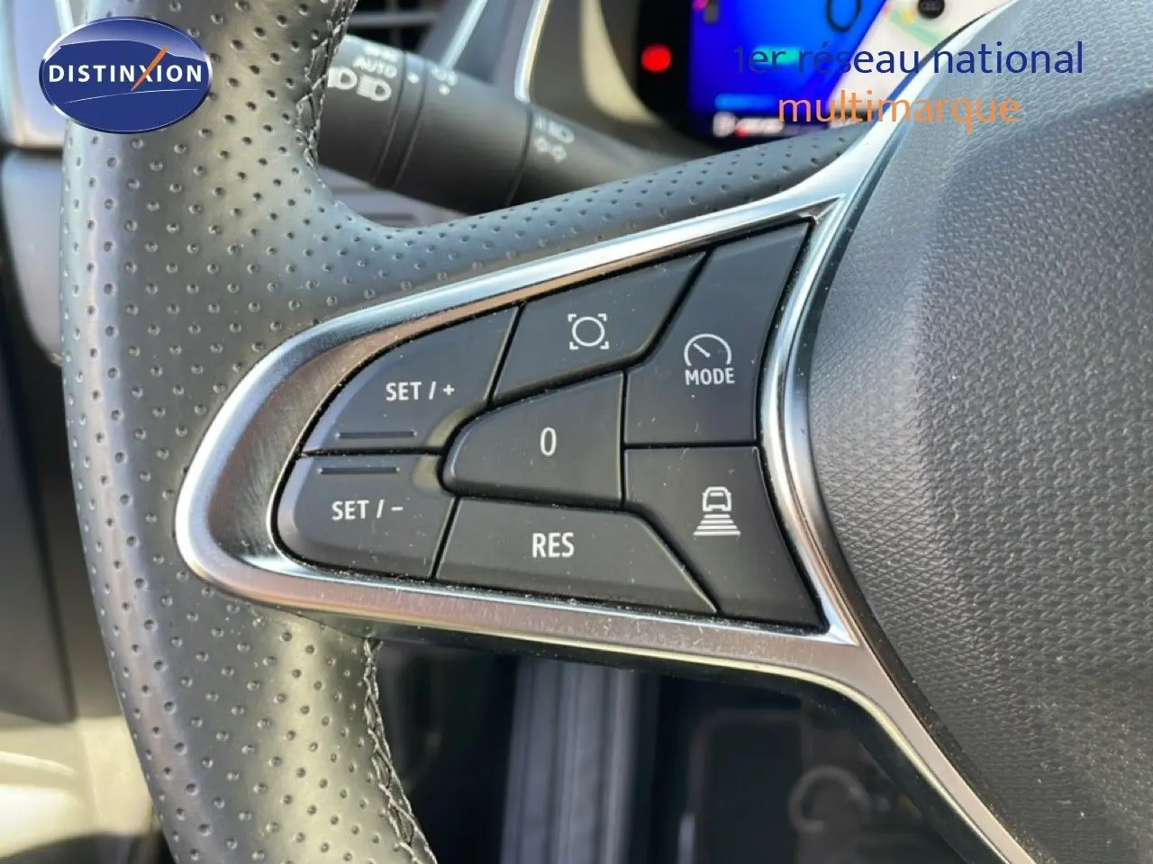 Gros plan sur les commandes au volant perforé noir du Renault Symbioz gris cassiopée, avec boutons de régulateur de vitesse.