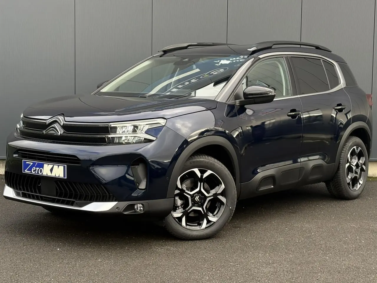 Citroën C5 Aircross Bleu Eclipse en 3/4 avant droit, avec jantes bi-ton et barres de toit noires brillantes.