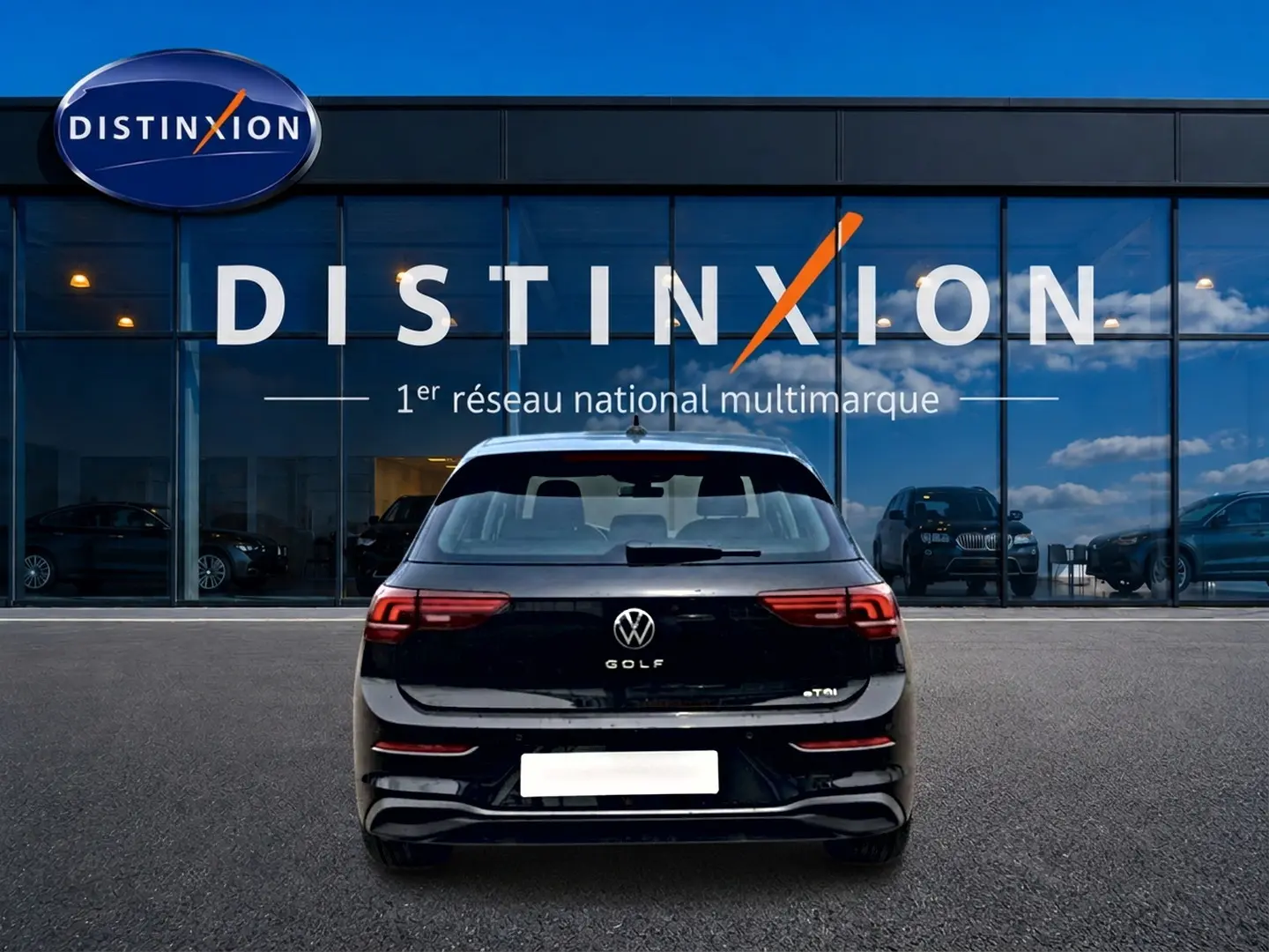 Vue arrière d'une Volkswagen Golf noire 2026 garée devant une vitrine avec logo Distinxion.