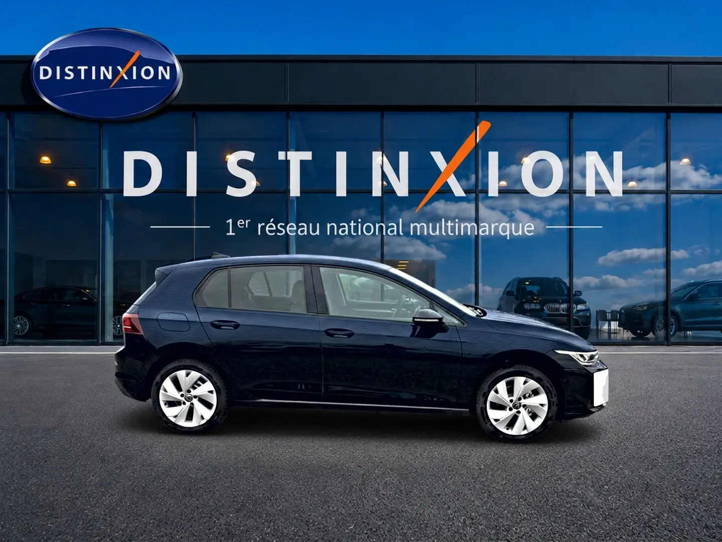 Profil côté gauche d'une Volkswagen Golf noire 2026 garée devant une vitrine avec logo Distinxion.