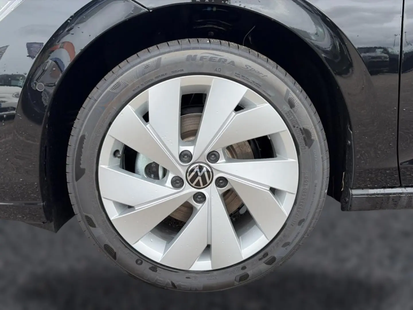 Gros plan sur la roue avant droite d’une Volkswagen Golf noire avec jante alu 17 pouces au design moderne.