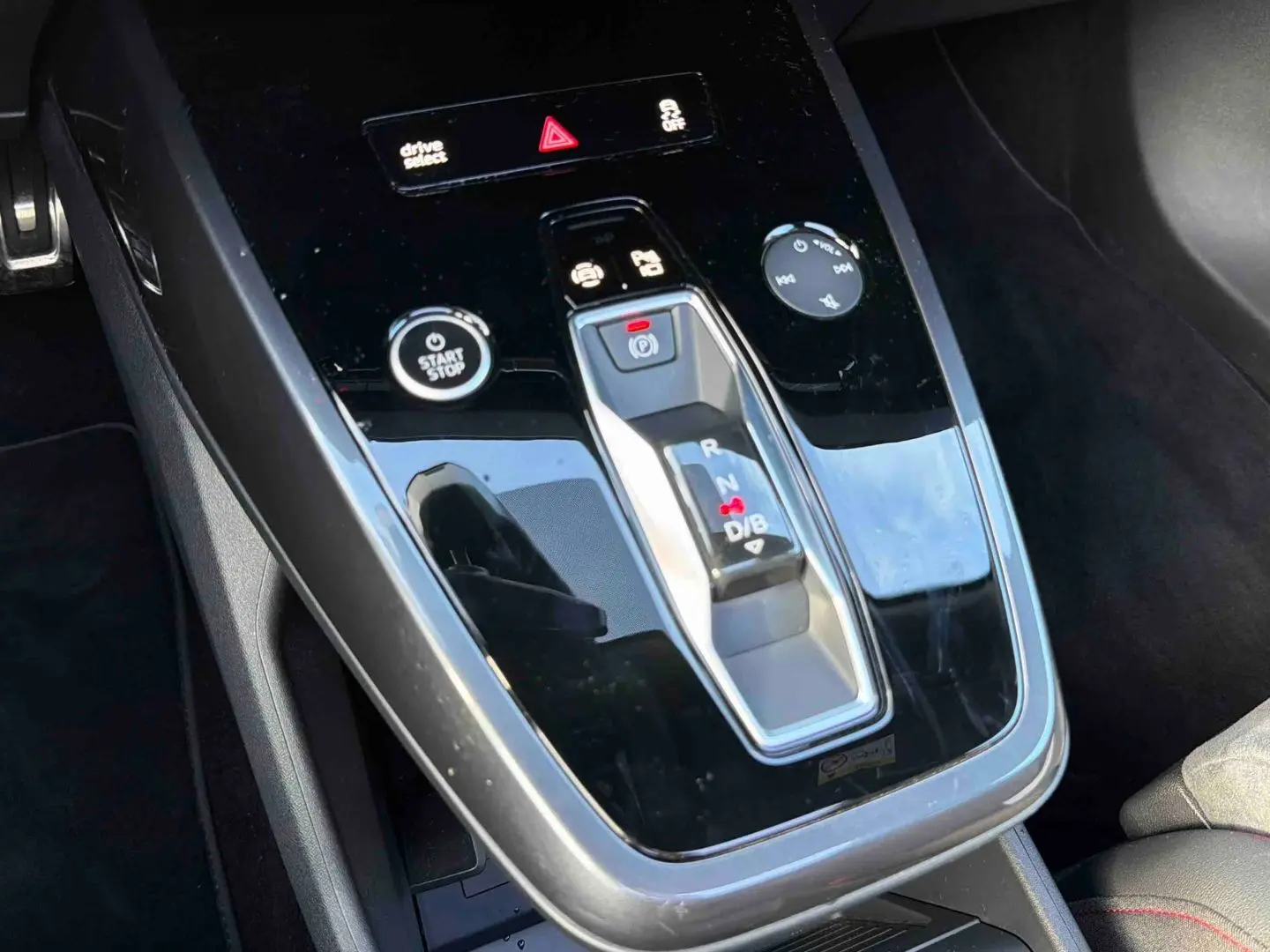 Gros plan sur la console centrale noire brillante de l'Audi Q4 e-tron 45 avec levier de vitesses automatique et boutons fonctionnels.