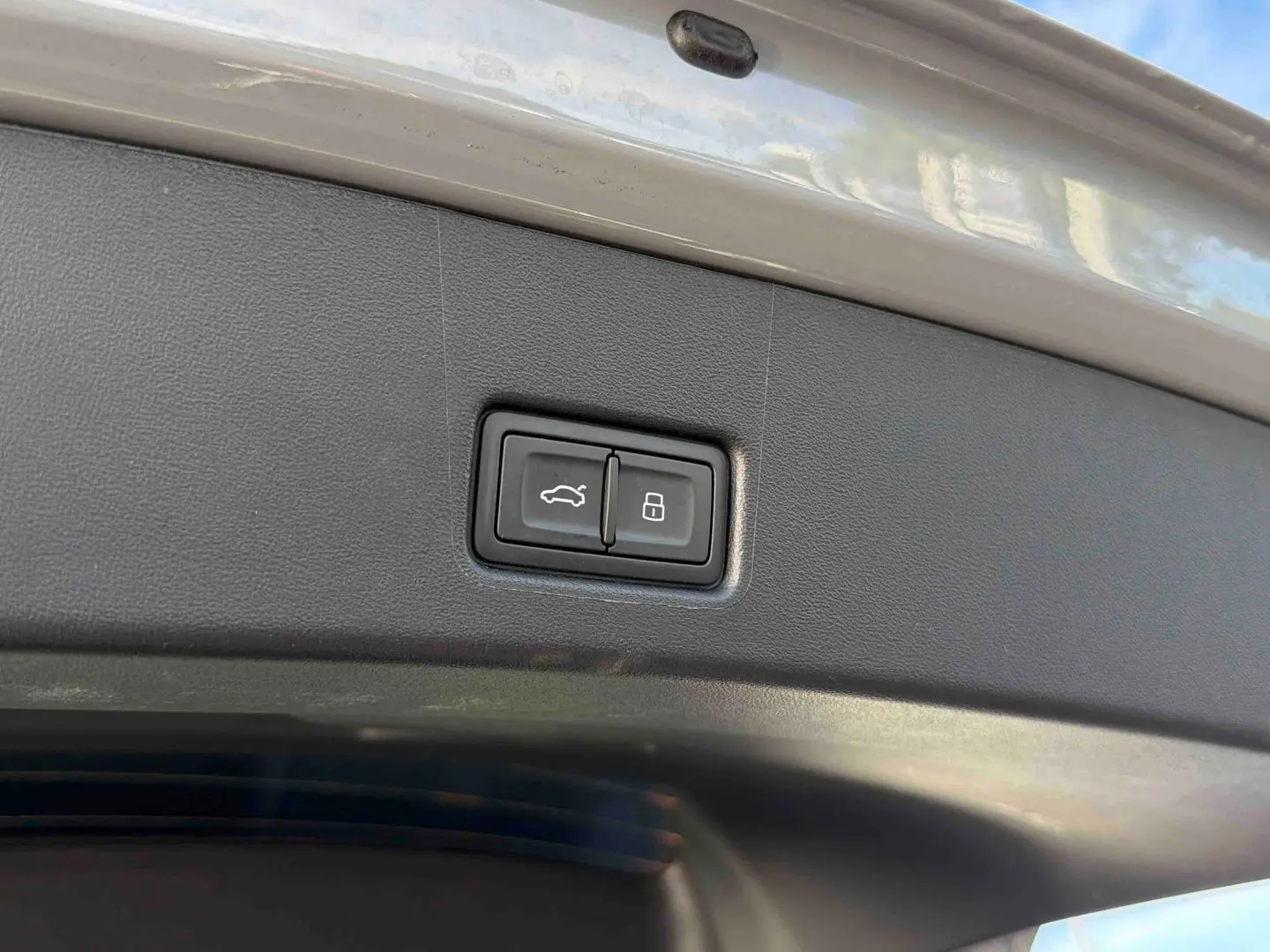 Gros plan sur les boutons d'ouverture et de verrouillage du hayon électrique du coffre d'un Audi Q4 e-tron gris galet.