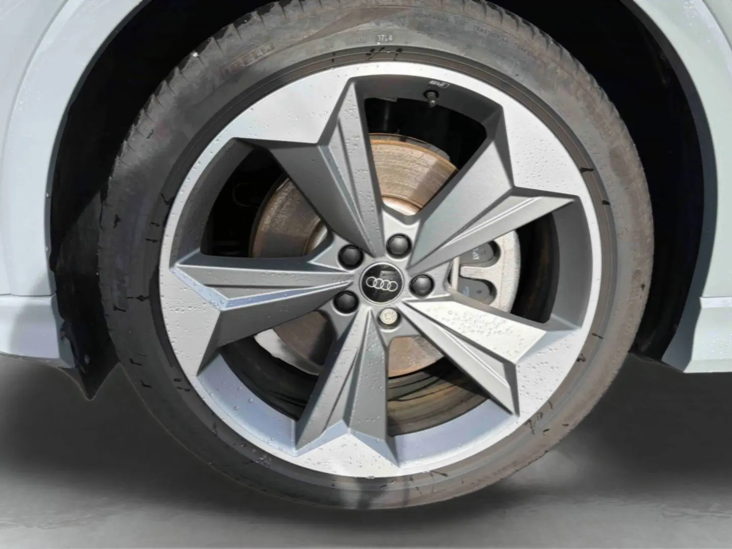 Gros plan sur la jante 19 pouces à 5 branches en étoile grise du côté avant droit de l'Audi Q4 e-tron gris galet.
