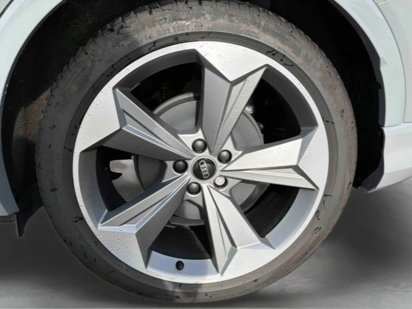Gros plan sur la jante 19 pouces à 5 bras en étoile de l'Audi Q4 e-tron gris galet, avec logo Audi au centre.