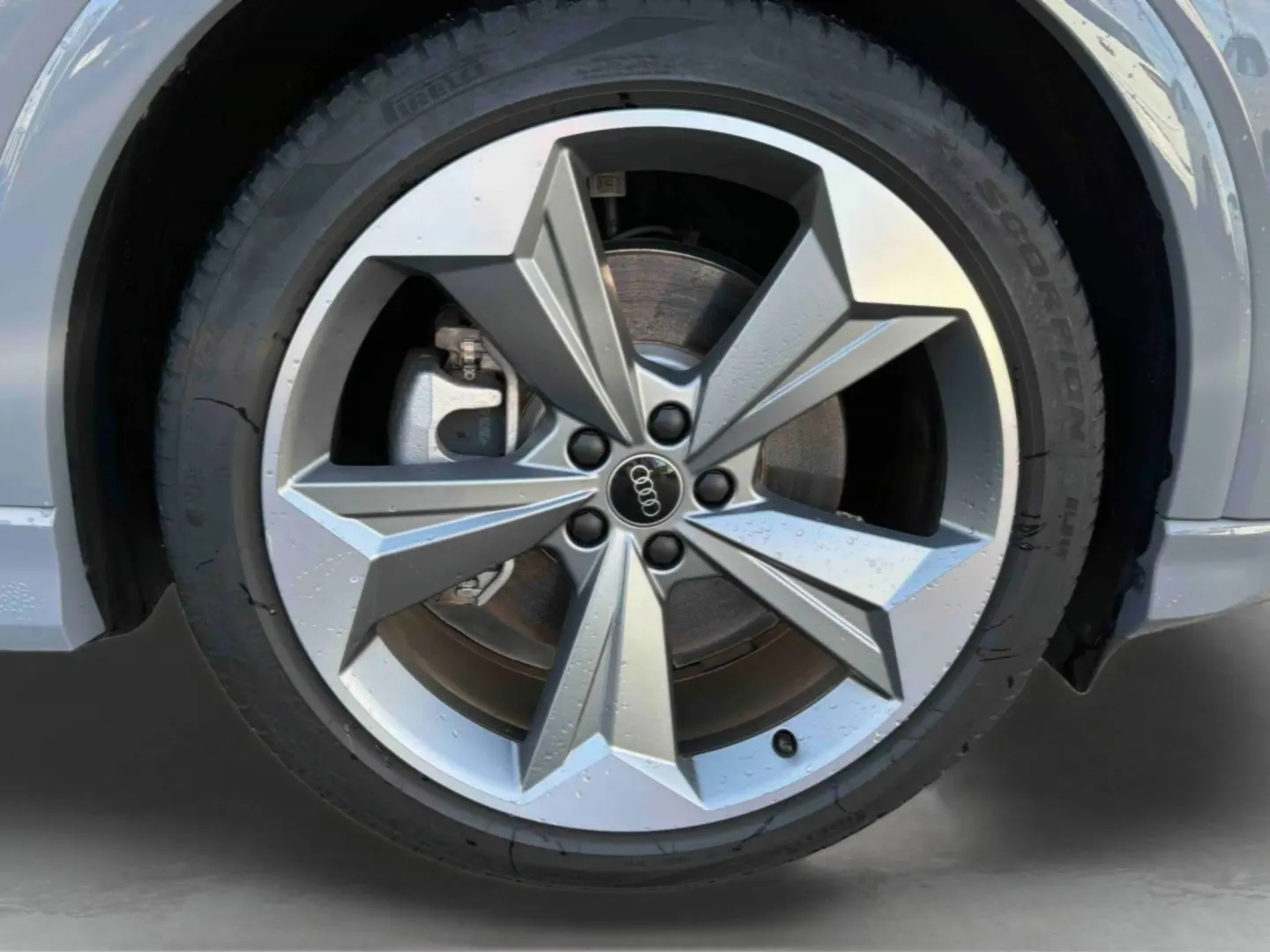 Gros plan sur la jante 19 pouces à 5 bras en étoile de l'Audi Q4 e-tron gris galet, avec pneu Pirelli visible.