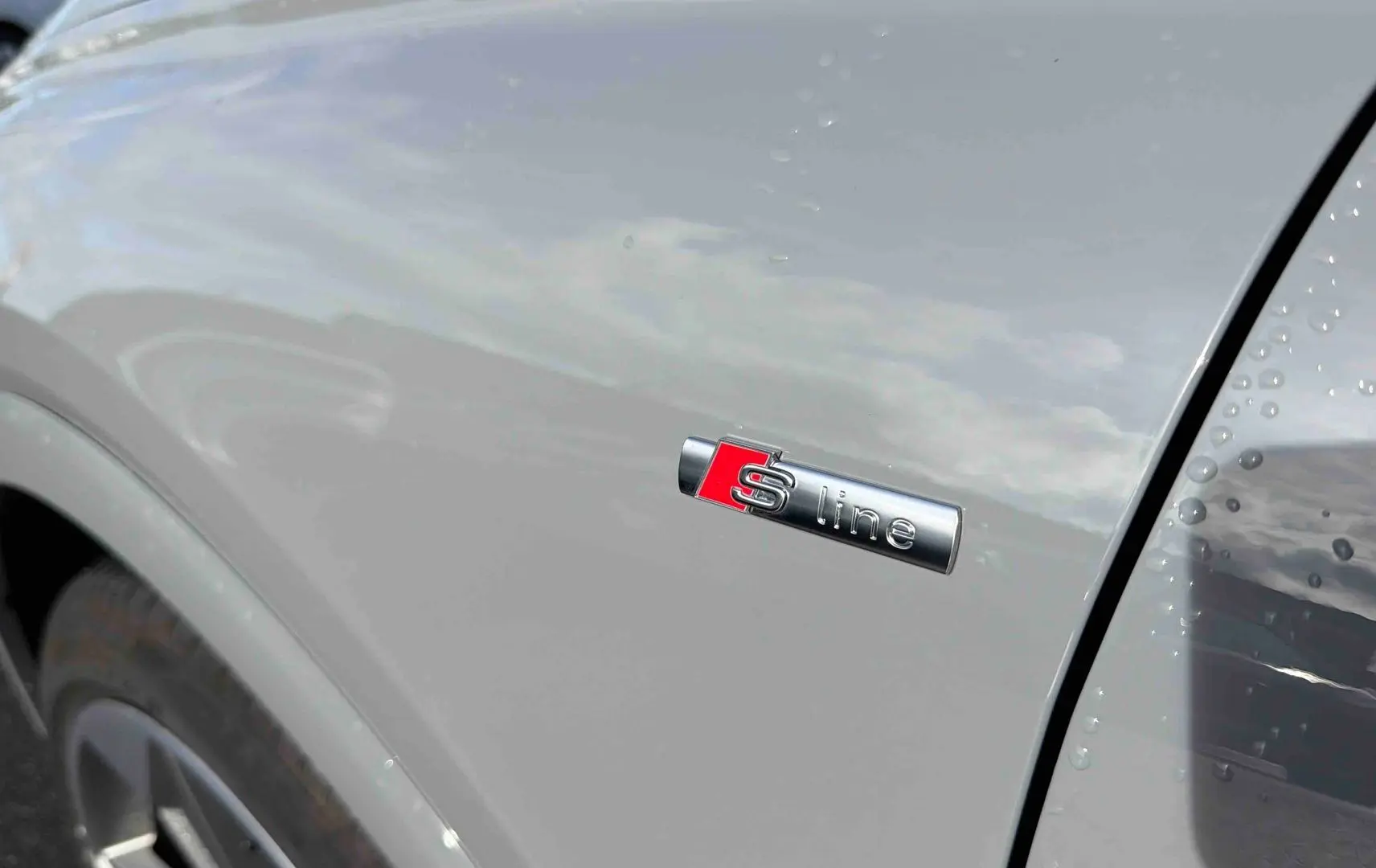 Détail de l'aile avant droite gris galet d'un Audi Q4 e-tron 45 avec badge S line et jante visible.