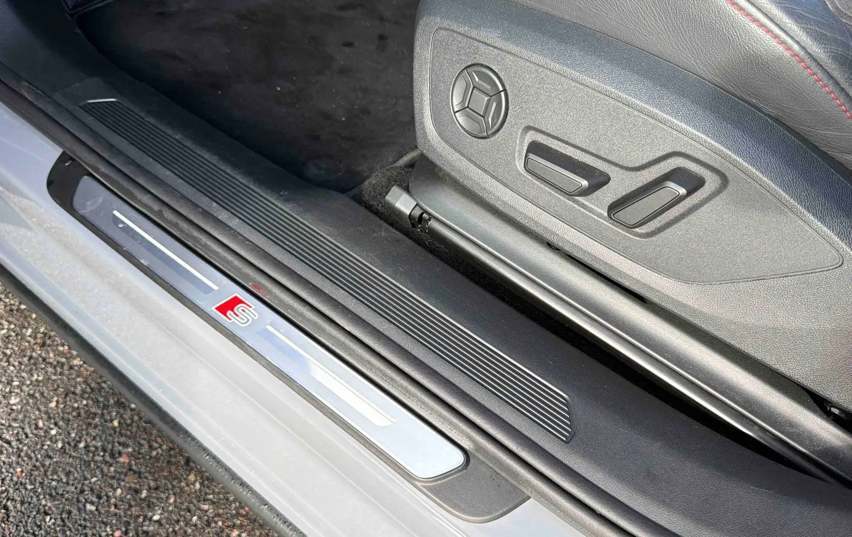 Détail de la marche d’entrée côté conducteur avec logo S sur Audi Q4 e-tron gris galet, siège en cuir noir.